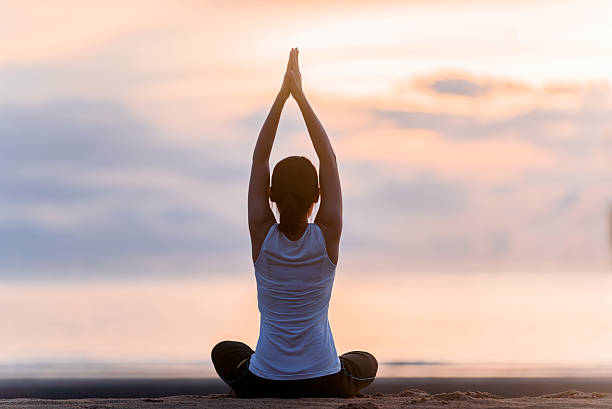 istock Young woman practicing yoga on the beach at sunset. 599715228