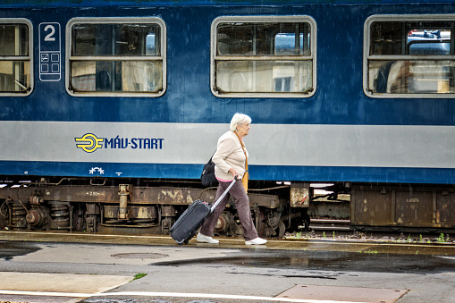 Budapest, Hungary - July 17, 2016: Passenger hurrying for a train. Woman pulling her suitcase on platform of Budapest Station in Hungary