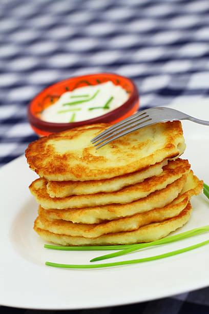 istock Stack of golden potato fritters on white plate with chives 599747858