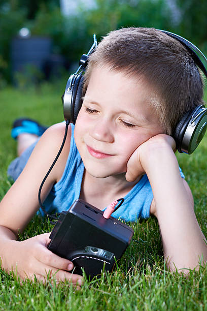 ragazzino sdraiato sull'erba con il vecchio lettore di audiocassette - one little boy audio foto e immagini stock