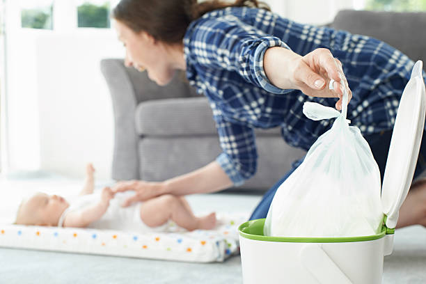 Mother Disposing Of Baby Nappy In Bin stock photo