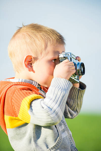 istock Little boy with an old camera shooting outdoor. 599750002