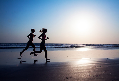 Couple running on the beach at sunset