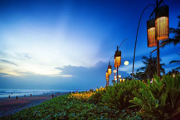 Seminyak Denpasar Bali Indonesia beach at sunset with elecric lanterns on one side.