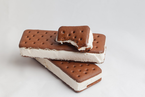 An isolated picture of three ice cream sandwiches stacked with the top on patially eaten.