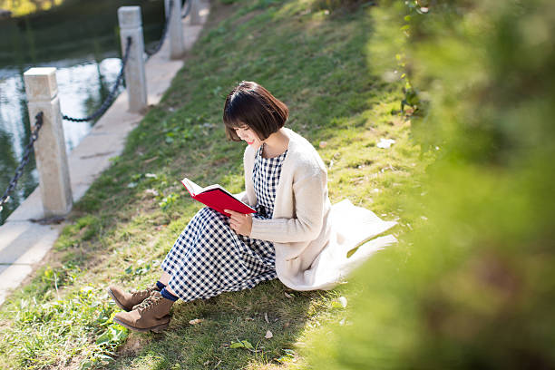 Woman Sitting On Field By Tree