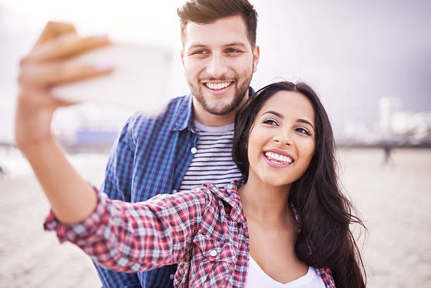 istock happy couple taking selfie on beach with smartphone 599765024