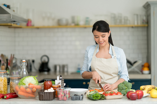 Happy Latin American woman looking very happy cooking dinner at home - lifestyle concepts