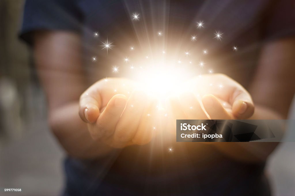 Stardust and magic in woman hands on dark background Giving Stock Photo