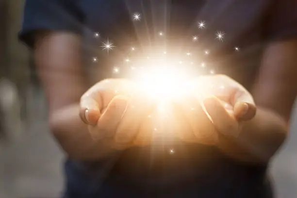 Photo of Stardust and magic in woman hands on dark background