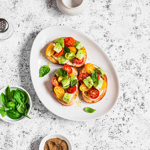 bruschetta con tomates cherry, aguacate y albahaca - brushetta fotografías e imágenes de stock