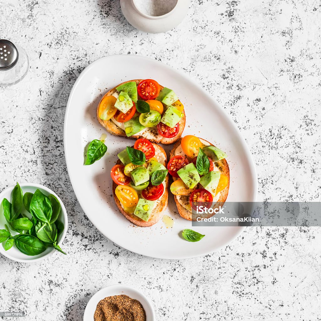 Bruschetta with cherry tomatoes, avocado and basil Bruschetta with cherry tomatoes, avocado and basil. On a light background. Healthy snack Bruschetta Stock Photo