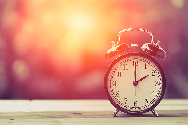 istock 2 o'clock Clock Vintage on Wood Table with Sun Light 599772356