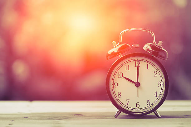 istock 10 o'clock Clock Vintage on Wood Table with Sun Light 599772576