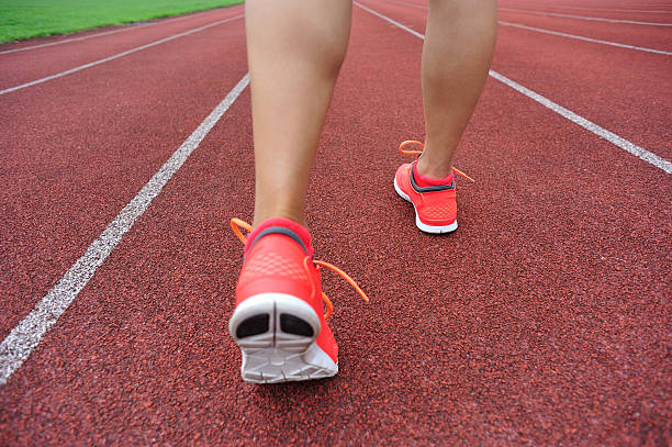 istock young woman runner legs on red running track in stadium 599772704