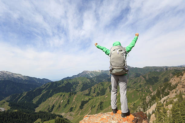 istock cheering successful woman backpacker open arms on mountain peak 599774444
