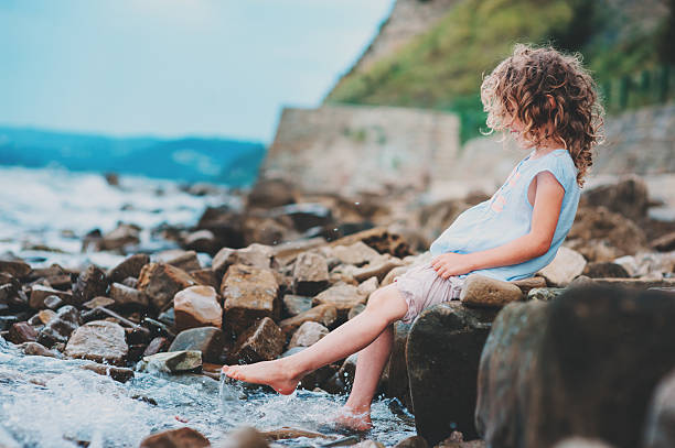 istock happy kid girl playing with water on the beach 599776008