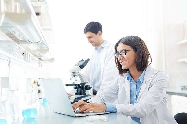 Typing in lab Happy scientist working with electronic data in lab laboratory chemist scientist medical research stock pictures, royalty-free photos & images