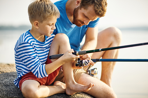 Father and son fishing on the lake, husband and child together on a picnic