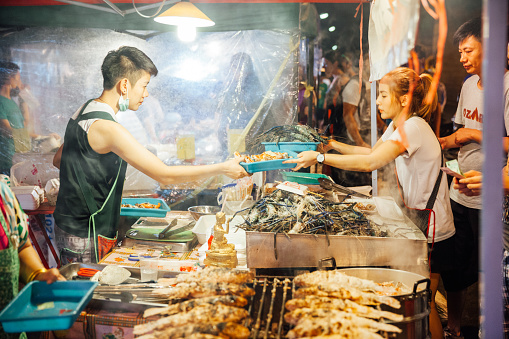 Chiang Mai, Thailand - August 27, 2016: Food vendor cooks and sells fish and seafood at the Saturday Night Market (Walking Street).