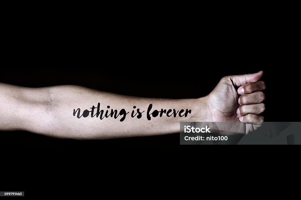 text nothing is forever in a forearm closeup of a young caucasian man with the text nothing is forever simulating a tattoo in his forearm, against a black background Tattoo Stock Photo