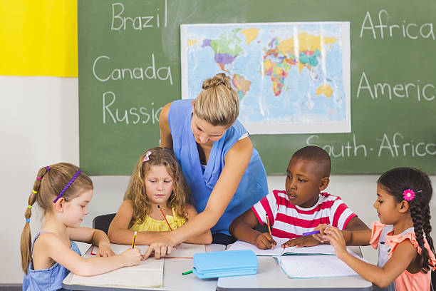 istock Teacher helping kids with their homework in classroom 599792192