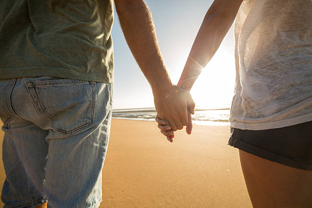 istock Young couple holding hands on the beach at sunset 599792514
