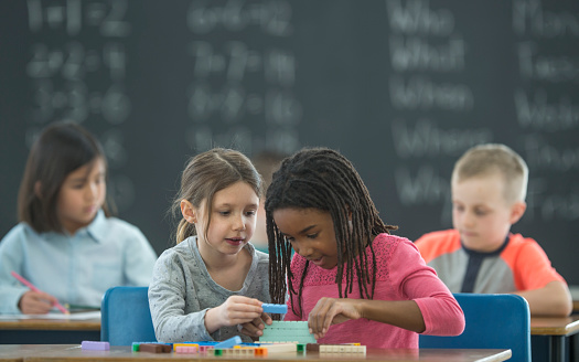 A multi-ethnic group of elementary age students are playing with blocks to learn mathematics.