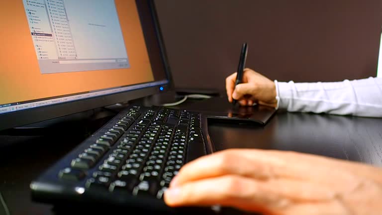 Tablet 26. Close up of the hand of a graphic designer holding an electronic stylus and open scheme on LCD monitor