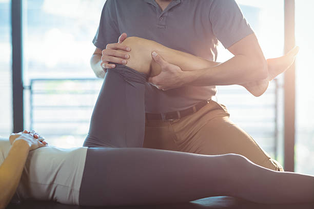 Physiotherapist giving knee therapy to a woman Physiotherapist giving knee therapy to a woman in clinic physical therapy stretching stock pictures, royalty-free photos & images