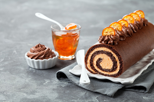 Chocolate swiss roll cake with candied kumquats, selective focus