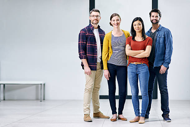 We're about to embark on success together Portrait of a group of creatives standing together in an office organized group photos stock pictures, royalty-free photos & images