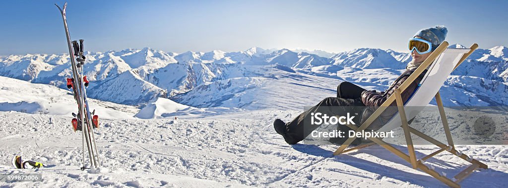 Girl sunbathing in a deckchair near a snowy ski slope Panorama of a girl sunbathing in a deckchair near a snowy ski slope Skiing Stock Photo