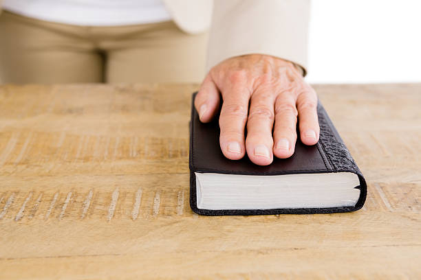 istock Midsection of woman with hand on bible 599872838