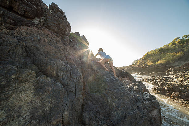 istock Young woman climbs steep rock, towards sunlight 599874354