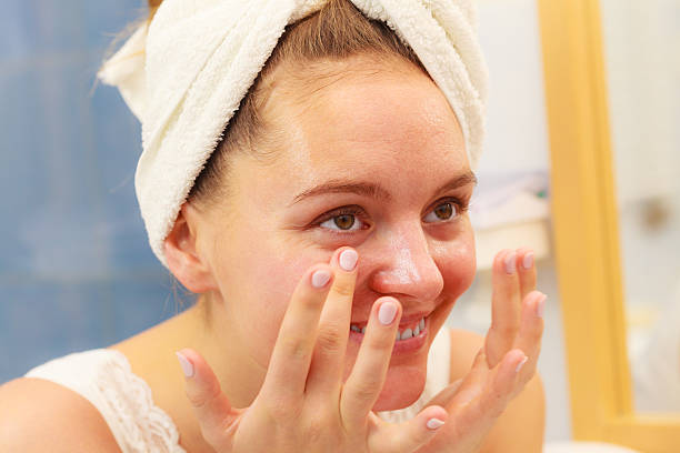 istock Woman applying mask cream on face in bathroom 599875742