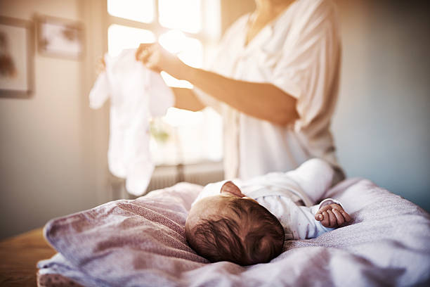 Let's get you ready for the day Shot of a mother changing her newborn baby girl at home lens flare offspring daughter human age stock pictures, royalty-free photos & images