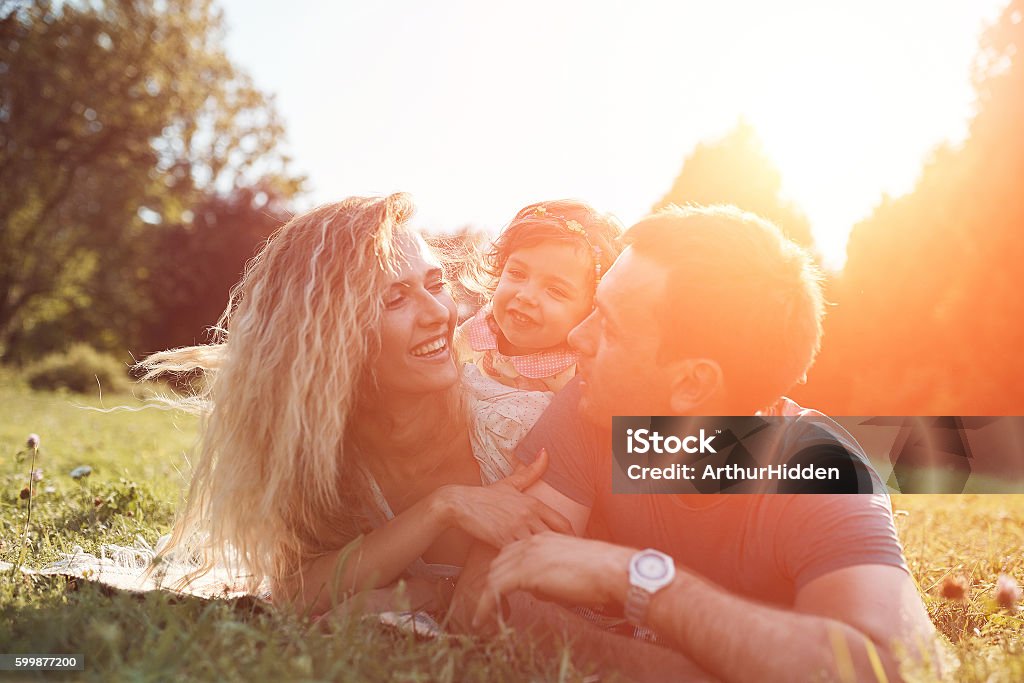 Happy young family spending time together outside in green nature. Beautiful happy family spending time together outside in green nature. Sunlight effect Family Stock Photo