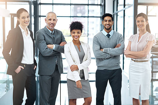 We strive to be the best team in the business Portrait of a happy group of colleagues standing together in a modern office organized group photos stock pictures, royalty-free photos & images