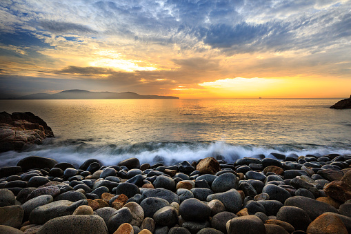 Long exposure of wave sea and the big pebbles, beautiful sunrise in beach Quy Nhon city, Vietnam