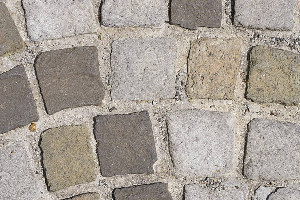 istock Cobble stones in concrete on a path, background texture macro 599881336