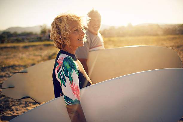 Never too old for surfing Very active senior couple getting ready to surf the waves on their active vacation never stock pictures, royalty-free photos & images