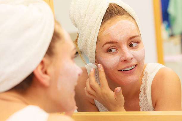istock Woman applying mask cream on face in bathroom 599882258