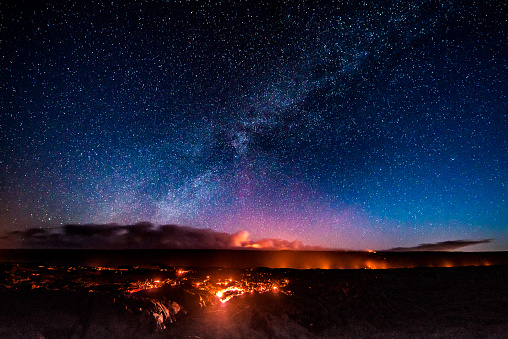 With the stars of the milky way overhead, lava from the Kilauea volcano finds it's way towards the Pacific ocean during the first light of a new day.