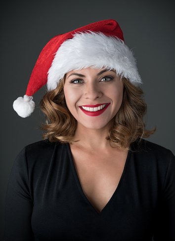 Portrait of a woman celebrating Christmas and looking very happy wearing a Santa hat