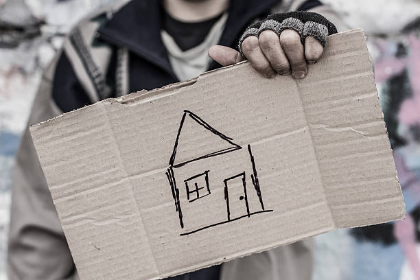 Praying for home Young homeless man holding sign with painted house begging social issue photos stock pictures, royalty-free photos & images