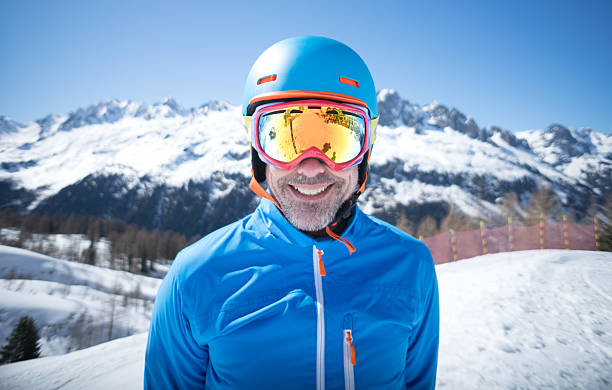 Happy adult man skiing Happy adult man skiing and looking at the camera wearing goggles and a helmet ski goggles stock pictures, royalty-free photos & images