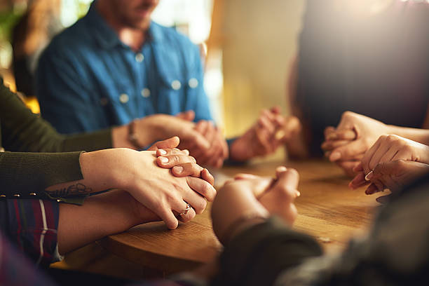 They share a strong faith Shot of a group of people holding hands and praying together prayer stock pictures, royalty-free photos & images