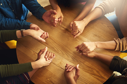 Shot of a group of people holding hands and praying together