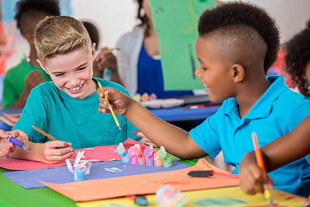 istock Elementary friends paint pictures in art class 599899980